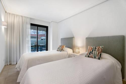 two beds in a room with a window at Balcón de Los Gigantes in Puerto de Santiago