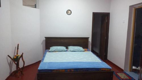 Schlafzimmer mit einem Bett mit einem Kopfteil aus Holz in der Unterkunft Kuchi Villa in Kalutara