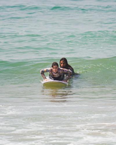 a woman and a child on a surfboard in the ocean at The Moroccan Surf House in Imsouane