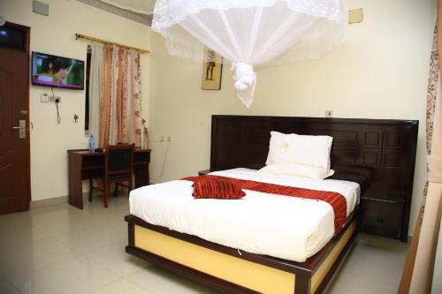 1 dormitorio con 1 cama con cabecero de madera en GLORY SUMMIT HOTEL HOIMA, en Hoima