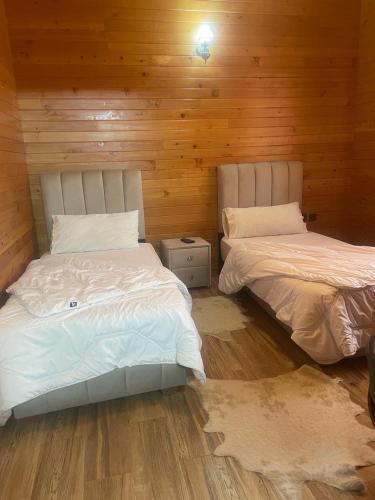 two beds in a room with wooden walls at Hôtel les truites in Imouzzer Kandar