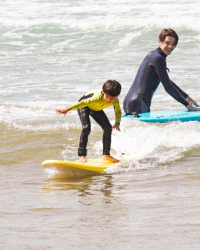 a young boy riding a wave on a surfboard in the ocean at The Moroccan Surf House in Imsouane