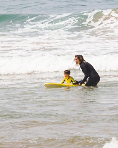 a woman and a child on a surfboard in the ocean at The Moroccan Surf House in Imsouane