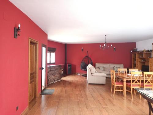 a living room with red walls and a table and a couch at Casa Rural EL ALMEZ in Horcajo de Santiago