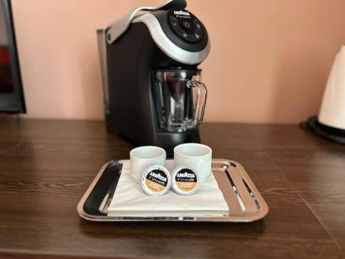 two coffee cups on a tray next to a coffee maker at Boutique Hotel Sopianae in Pécs