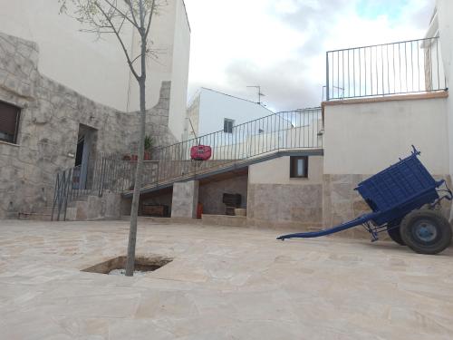 a blue cart next to a building with a tree at Casa Rural EL ALMEZ in Horcajo de Santiago