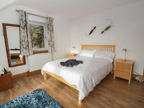 a bedroom with a white bed and a mirror at Merse End in Dalbeattie