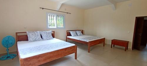 a bedroom with two beds and a window at Chambre D'hôtes Morondava in Morondava