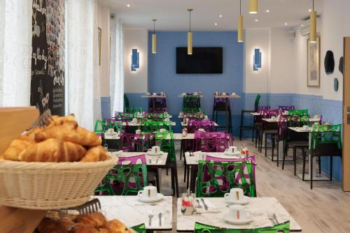 a dining room with tables and chairs and a basket of bread at Hôtel Byakko Nice in Nice