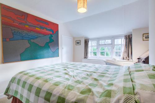 a bedroom with a bed and a painting on the wall at Charming Hilltop Cottage with Panoramic Views in East Worldham