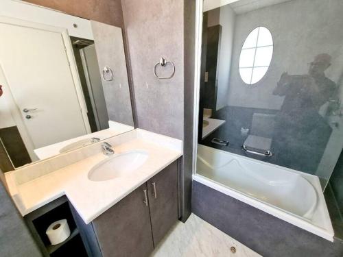 een badkamer met een wastafel, een bad en een spiegel bij Private pool/Sleep 6/15 mins drive to beach/Marina in Dubai
