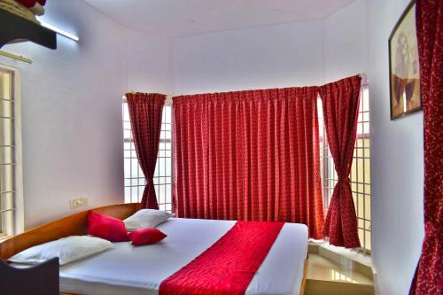 Schlafzimmer mit einem großen Bett und roten Vorhängen in der Unterkunft Peters Park in Yelagiri