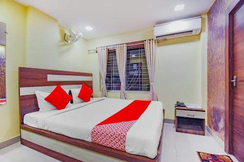 a bedroom with a bed with red pillows and a window at Hotel O Tranquil Stay in Kolkata