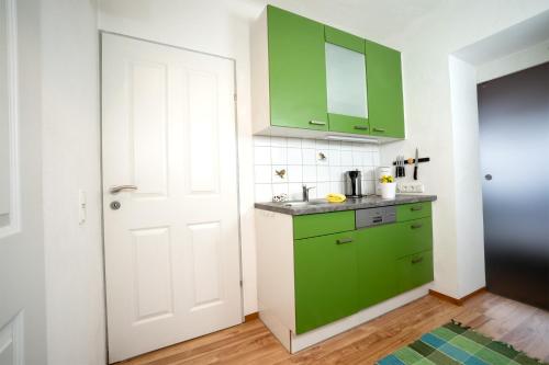 uma cozinha com armários verdes e uma porta branca em Bahnwärterhaus em Pregarten