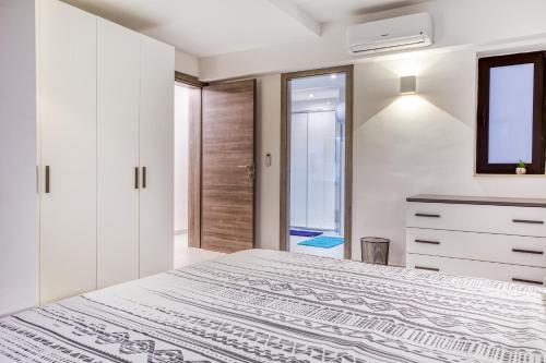 a white bedroom with a large bed and a window at Stylish & Cosy 1BR home with Balcony in St Julians BY 360 Estates in Tal-Għoqod