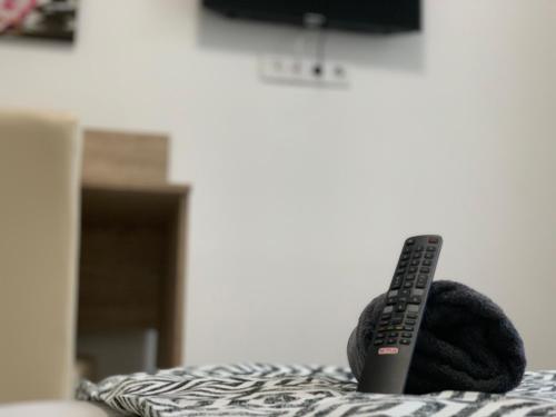 un mando a distancia sentado sobre una cama en Tiny Apartments, en Miskolc