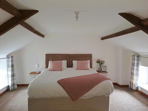 a bedroom with a large bed with pink pillows at Celtic Minor Cottage in Ystalyfera