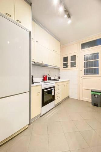 a kitchen with white cabinets and a refrigerator at Syntagma square, 65sqm cozy family apartment in Athens