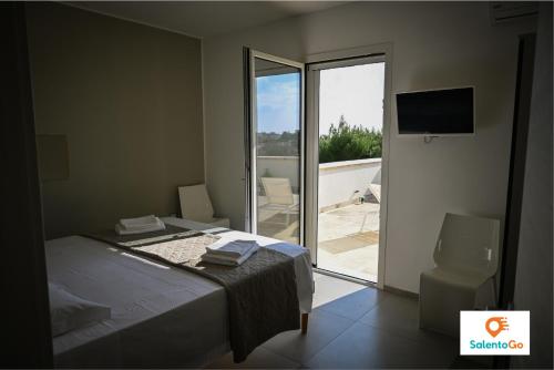 a bedroom with a bed and a sliding glass door at Stanze VILLA DEL CONTE a Punta Prosciutto by SalentoGo in Punta Prosciutto