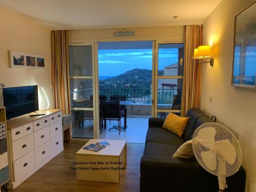 a living room with a couch and a large window at "Location Vue MER et ESTEREL", Cap Estérel Agay-Saint Raphaël, T2, piscines, parking, wifi in Saint-Raphaël