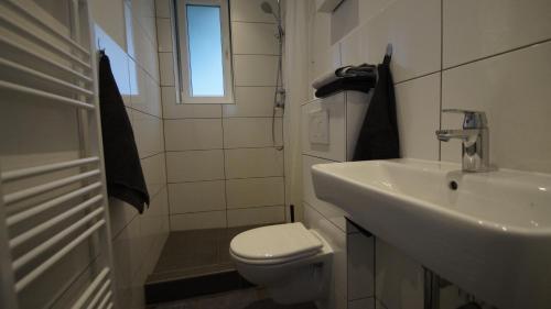 a white bathroom with a toilet and a sink at Ferienwohnung Best Apartments Leverkusen 2 in Leverkusen
