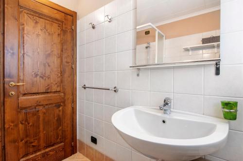 a bathroom with a sink and a wooden door at Residence Larice Bianco App n3 in Campodolcino
