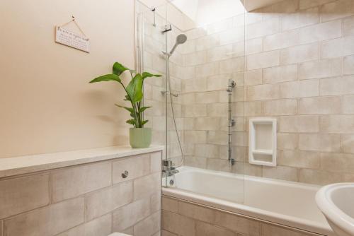 a bathroom with a shower and a tub and a sink at Little Ripple Cottage by Bloom Stays in Canterbury
