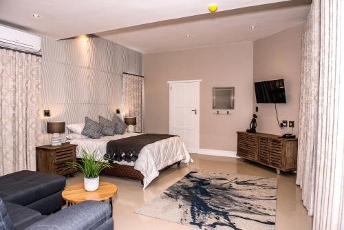 a bedroom with a bed and a couch and a tv at K Partners' Boutique Hotel & Spa in Langebaan
