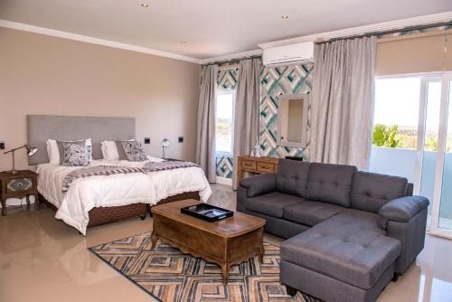ein Schlafzimmer mit einem Bett, einem Sofa und einem Tisch in der Unterkunft K Partners' Boutique Hotel & Spa in Langebaan