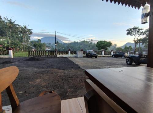 a patio with a table and chairs and a parking lot at Indah Damai Cottages in Sidomukti