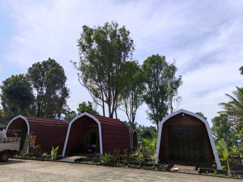 two yurt buildings with trees in the background at Indah Damai Cottages in Sidomukti