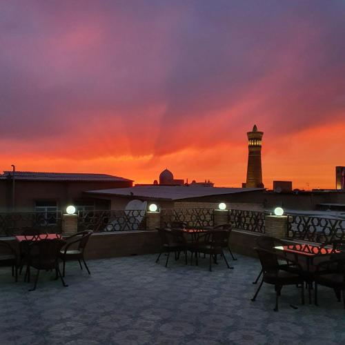 a patio with tables and a lighthouse at sunset at Hotel in Bukhara