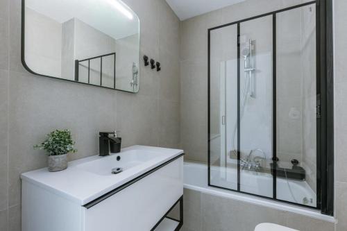 een witte badkamer met een wastafel en een spiegel bij Cosy studio near the beach in Oostende