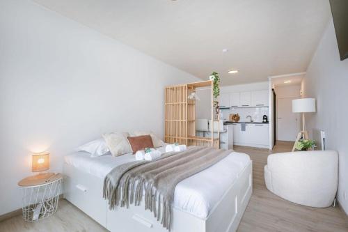 een witte slaapkamer met een groot bed en een keuken bij Cosy studio near the beach in Oostende