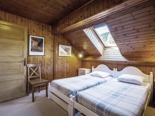 a bedroom with two beds and a window and a chair at Chalet La Clusaz, 5 pièces, 8 personnes - FR-1-304-108 in La Clusaz