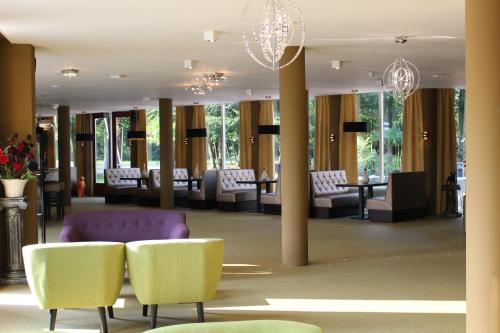 een lobby met stoelen, tafels en kroonluchters bij Hotel De Elderschans in Aardenburg