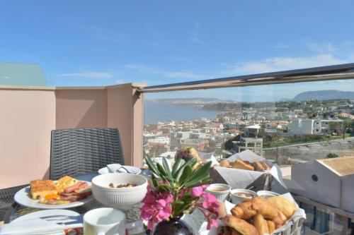 a table with food and a view of a city at Galini Sea View Hotel in Agia Marina Nea Kydonias
