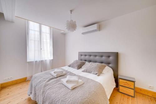 une chambre avec un grand lit avec des serviettes dessus dans l'établissement Logis Guadet, magnifique appartement dans Saint Emilion, à Saint-Émilion