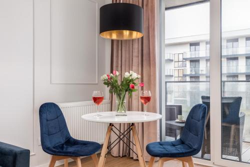 a table with two blue chairs and a vase of flowers at Wellness Resort & SPA Dziwnów Apartments with Parking by Noclegi Renters in Dziwnów