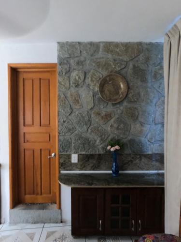 Zimmer mit einer Steinmauer und einer Vase mit Blumen in der Unterkunft Chalet la Adornada in Taxco de Alarcón