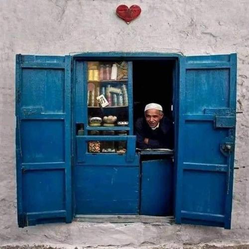 a man looking out the window of a blue door at Casa Marwan in Tetouan