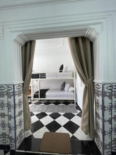 a room with a bed with curtains and a checkered floor at Casa Marwan in Tetouan