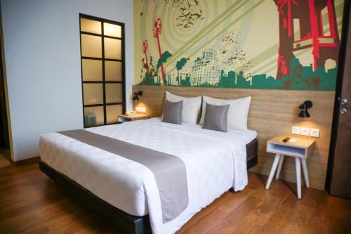 a bedroom with a large bed and a painting on the wall at Hotel Fortunagrande Jember in Jember