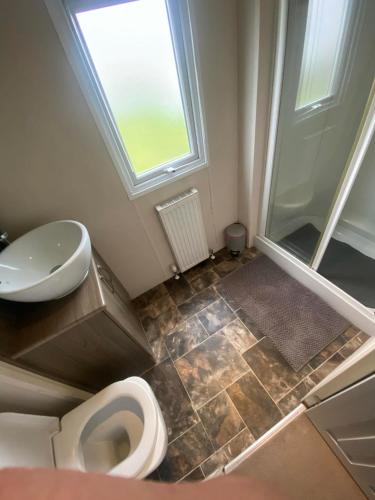 La salle de bains est pourvue de toilettes, d'un lavabo et d'une douche. dans l'établissement Impeccable 2-Bed Lodge in Ashington, à Ashington