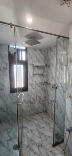 W łazience znajduje się prysznic ze szklanymi drzwiami. w obiekcie Chopra Residency w mieście Hamīrpur