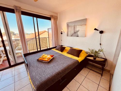 Bett in einem Zimmer mit einem großen Fenster in der Unterkunft Studio moderne à la plage in Canet-en-Roussillon