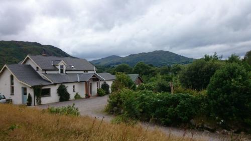 a white house with mountains in the background at Kenmare Eco Lodge in Kenmare