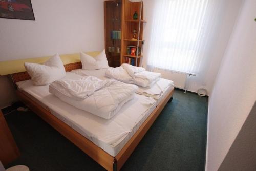 um quarto com uma cama com lençóis brancos e almofadas em Ferienhaus Helder em Dorum Neufeld