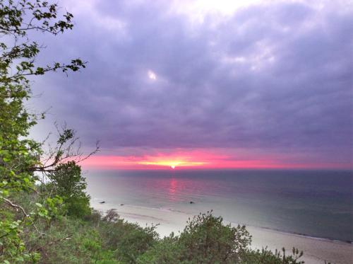 a sunset over a beach with the sun setting at Hotel & Restaurant Zum Kap Arkona in Putgarten