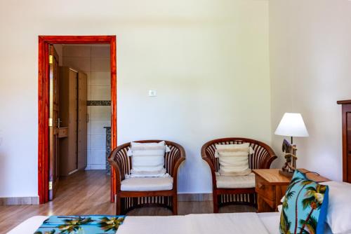 a bedroom with two chairs and a bed and a mirror at Chez Marston in La Digue